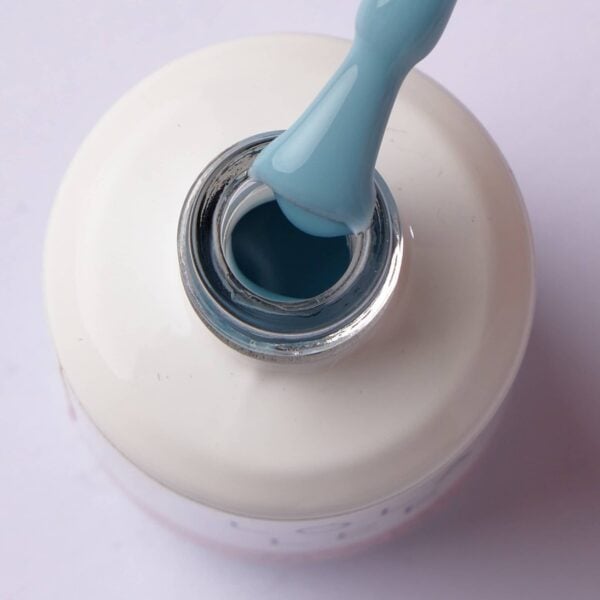 Brush lifting pastel baby blue gel polish from the bottle